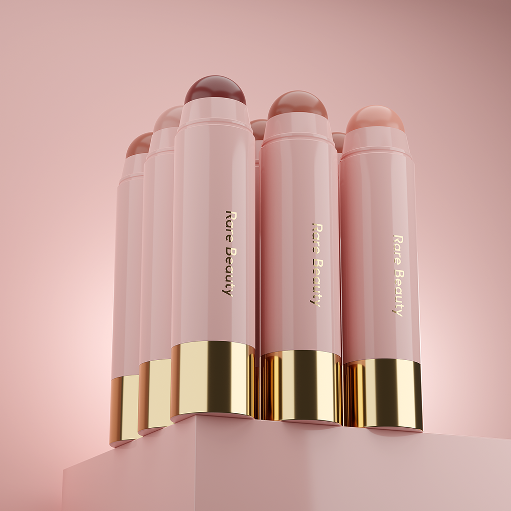A collection of Rare Beauty concealers places on a pink podium